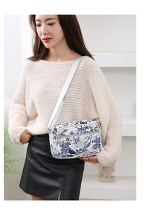Detail view of floral nylon crossbody bag with adjustable grey strap on model