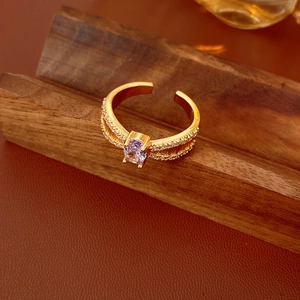 Detail eines goldenen verstellbaren Rings mit ovalem lila Zirkon und Bandstruktur