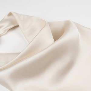 Close-up of elegant champagne satin fabric showing silky texture and draped folds