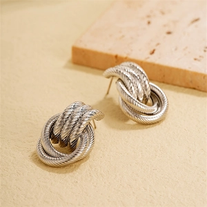 Detail view of silver knotted hoop earrings with fine twisted rope texture and minimalist design