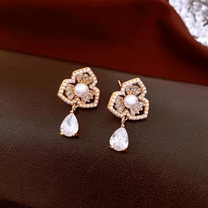 Macro shot of gold floral earrings with pearls and a teardrop crystal drop pendant