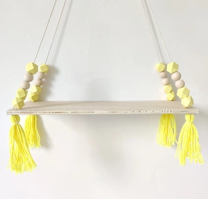 Detail of wooden hanging shelf with yellow tassels and geometric macaron beads