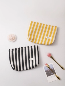 Minimalist striped canvas makeup bags in yellow and black patterns on white background