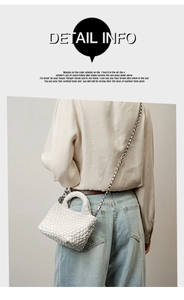 Detail shot of a white woven crossbody bag with a sleek silver metal chain strap