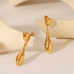 Macro shot of 18K gold plated stainless steel teardrop earrings on a white stone background