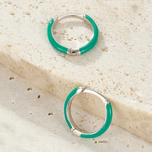 Close-up of S925 sterling silver hoop earrings with emerald green enamel on stone surface
