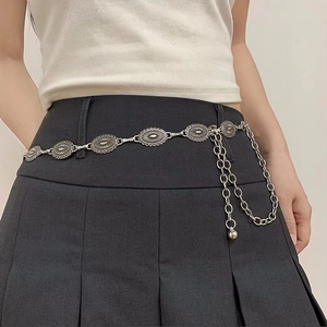 Detail of vintage silver boho concho waist belt with layered chains on a black skirt