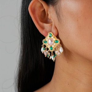 Close-up of vintage gold tassel earrings with pink crystals and green gemstones