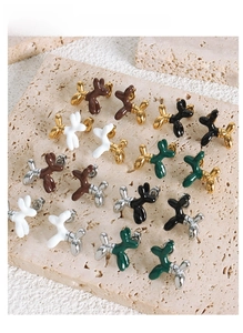 Detail shot of colorful enamel balloon dog earrings on a travertine stone surface
