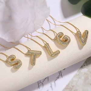 Elegant gold necklaces with micro-pave zircon letter pendants on white pedestals