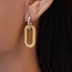 Macro shot of 18k gold plated interlocked earrings with spiral texture and silver ring