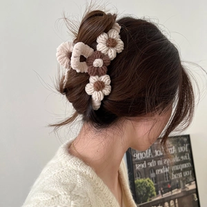 Detail of knitted cream flower hair claw clip on model's hair with soft knit texture