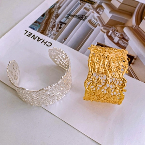 Macro view of wide lava texture open bangles in polished gold and silver finishes