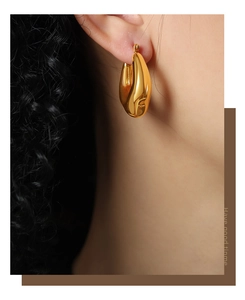 Close-up of elegant gold water drop earrings worn by a model for a chic style