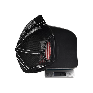 Detailed weight measurement showing a lightweight black trucker hat at 67.2g on a digital scale