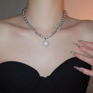 Detail of elegant pearl pendant with zircon rhinestone chain and gray beaded necklace