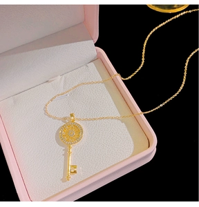 Macro shot of gold key pendant with sparkling zircons on a pink jewelry gift box