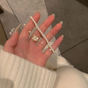 Detalle de una elegante pulsera de doble capa con perlas y colgante de camelia