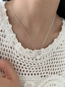 Dettaglio del ciondolo a cuore in argento con perla indossato sul décolleté