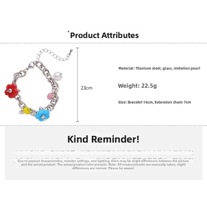 Detail view of a steel charm bracelet featuring colorful flowers and faux pearl beads