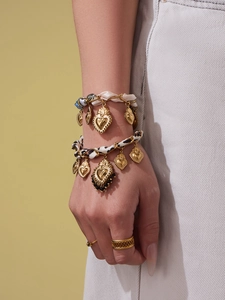 Dettaglio di bracciali dorati a strati con ciondoli a cuore e cinturini in tessuto blu