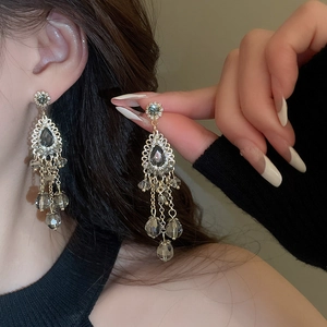 Close-up of golden teardrop tassel earrings with grey crystals in vintage palace style
