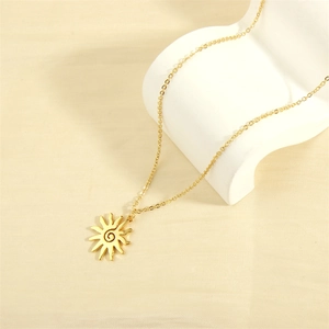 Close-up of golden solar spiral pendant necklace on a minimalist artistic display stand