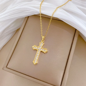 Close-up of golden cross pendant necklace with sparkling cubic zirconia on jewelry box