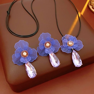 Detail of three purple flower necklaces with faceted crystal teardrops on brown leather