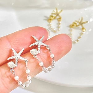 Macro detail of starfish earrings with tassels, pearls and rhinestones in gold and silver
