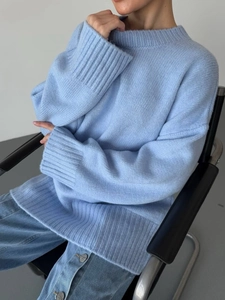 Close-up of soft light blue knit texture and round neckline on oversize sweater