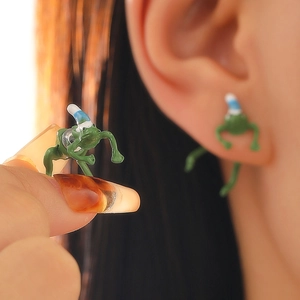 Quirky green frog stud earrings with Christmas hats shown on ear and held by hand