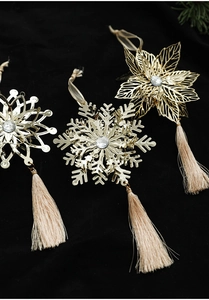 Detailed view of golden metal snowflake ornaments with crystal and champagne silk tassels