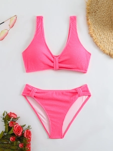 Detailed flat lay of pink waffle-textured two-piece bikini set with vacation accessories