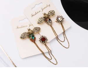 Detail of vintage gold bee and flower chain brooches with green and clear crystals