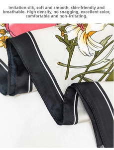 Macro detail of faux silk scarf featuring cream lily floral print and black piped edges