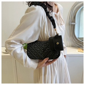 Close-up of black quilted shoulder bag with ruched strap and small detached coin purse