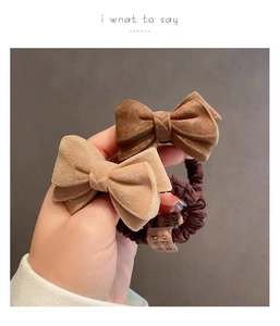 Detail of plush bow hair scrunchies in dark brown and beige with Hand Made label