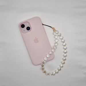 Elegant white shell beaded phone charm with gold accents on a pink smartphone accessory