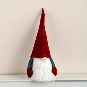 Christmas gnome doll in red felt hat and gray body on white surface tabletop decor