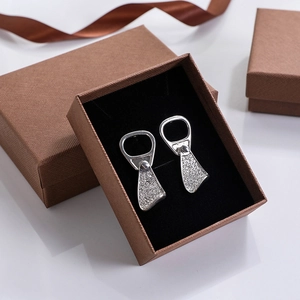 Dettaglio di orecchini a linguetta d'argento con zirconi bianchi in scatola regalo marrone