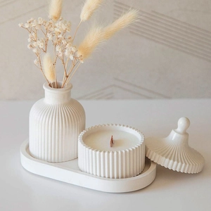 Detail view of striped resin jars and oval tray with a wooden wick candle and dried flowers