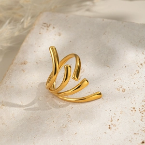 Macro detail of a 18k gold plated multi-layer spiral ring on a textured stone surface