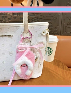 Detailed view of a cute pink plush slipper keychain hanging on a white handbag