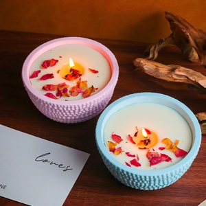 Detail van brandende geurkaarsen in roze en blauwe potten met gedroogde rozenblaadjes