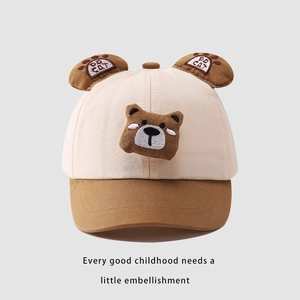 Dettaglio ricamo e orecchie 3D su cappellino in cotone beige e marrone per bambini