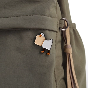 Macro shot of cute white enamel swan brooch with toast on a green nylon bag texture