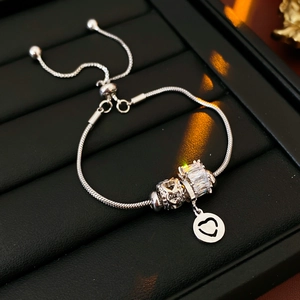 Close-up of beaded silver bracelet with heart pendant and crystals on black leather background