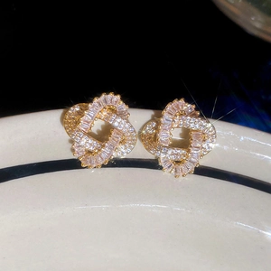Macro shot of gold plated earrings featuring intertwined cubic zirconia stones and crystals