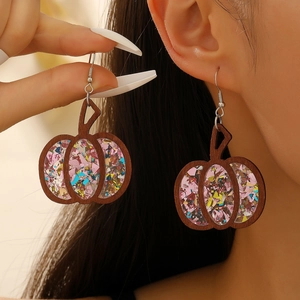 Detail of wooden pumpkin earrings with colorful glitter filling on a model's ear